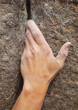 A hand jammed in a crack, thumb tucked into the palm