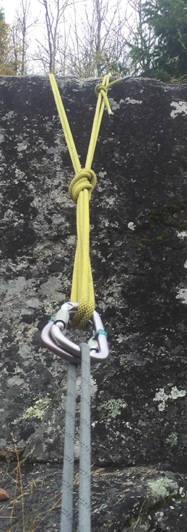 A yellow webbing anchor on a boulder, joined at a locking carabiner