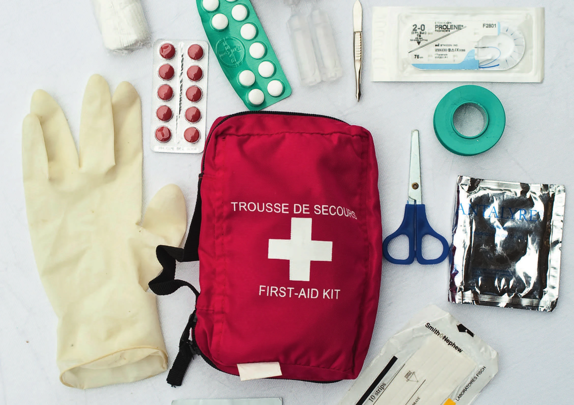 Une trousse de premiers soins d’escalade ouverte, avec gants, médicaments, ruban adhésif, ciseaux, sutures et scalpel
