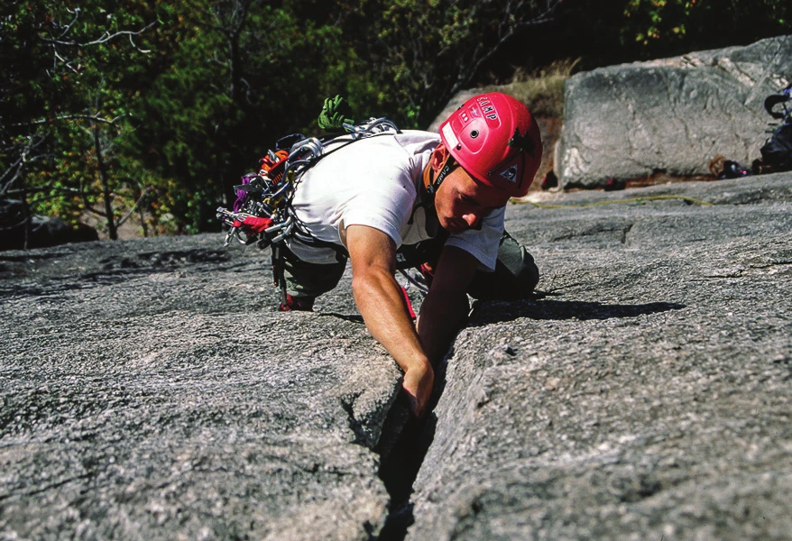 Un grimpeur coinçant une main dans une fissure de granite sur une dalle peu inclinée
